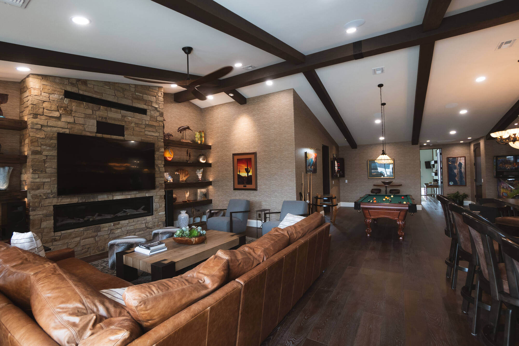 Game room featuring a leather sofa and large TV with stone fireplace in a custom home by MGD Builders in Phoenix, AZ