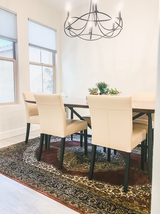 Elegant dining area featuring a dark wood table, beige upholstered chairs, and a large, ornate area rug.