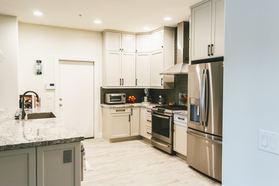 Contemporary kitchen featuring light cabinetry, granite countertops, and stainless steel appliances.