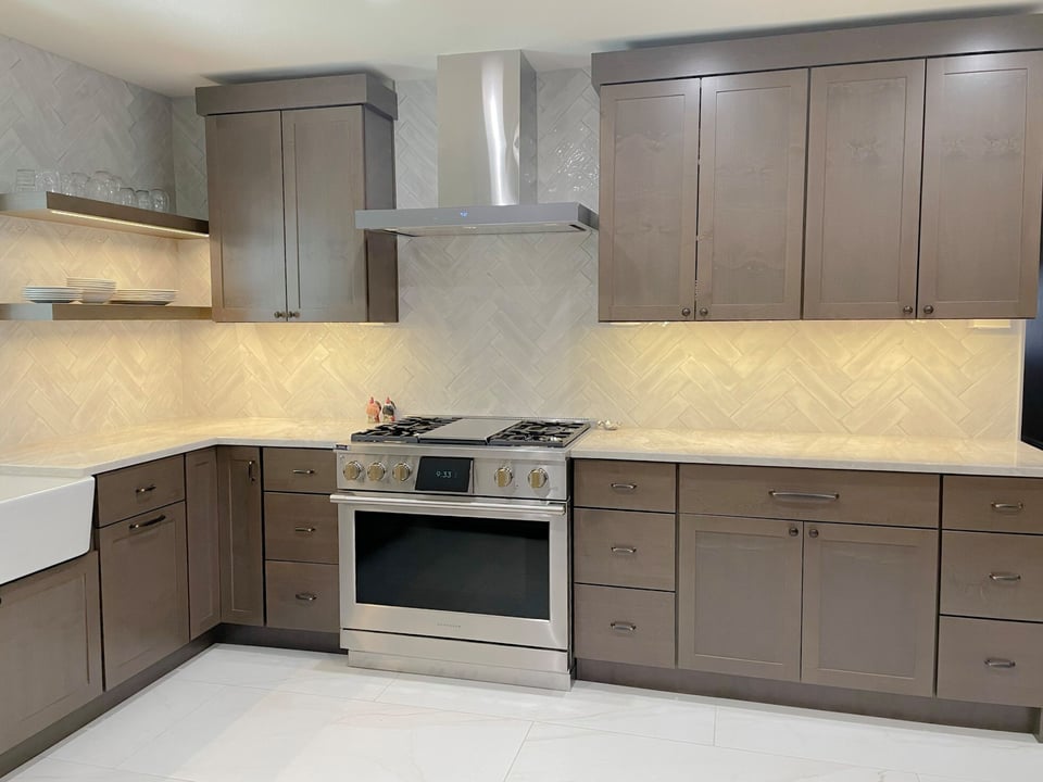 Modern kitchen with sleek dark cabinetry, a stainless steel stove and range hood, and a farmhouse sink.