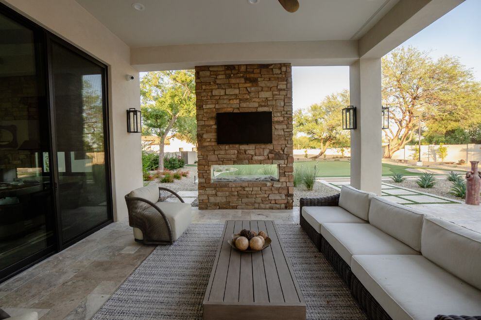 Exterior home remodel with outdoor fireplace, tv, and seating area