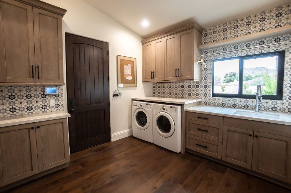 Custom laundry room with dark wood door and plenty of cabinets