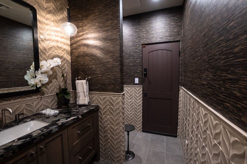 Dark bathroom remodel with wooden door and textured wall