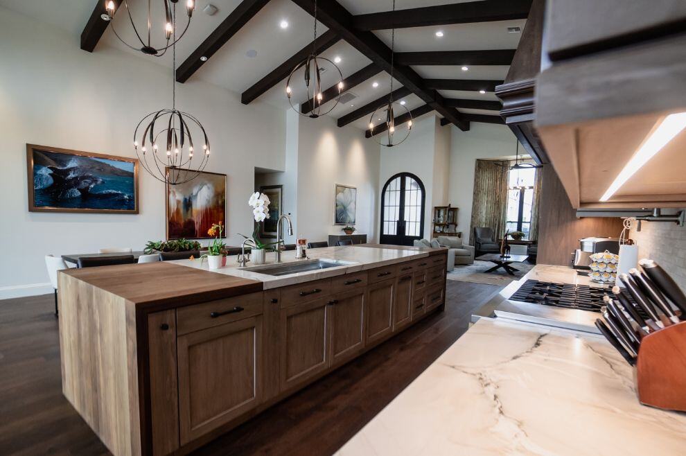 Open layout home renovation featuring exposed beams, kitchen island, and custom lighting