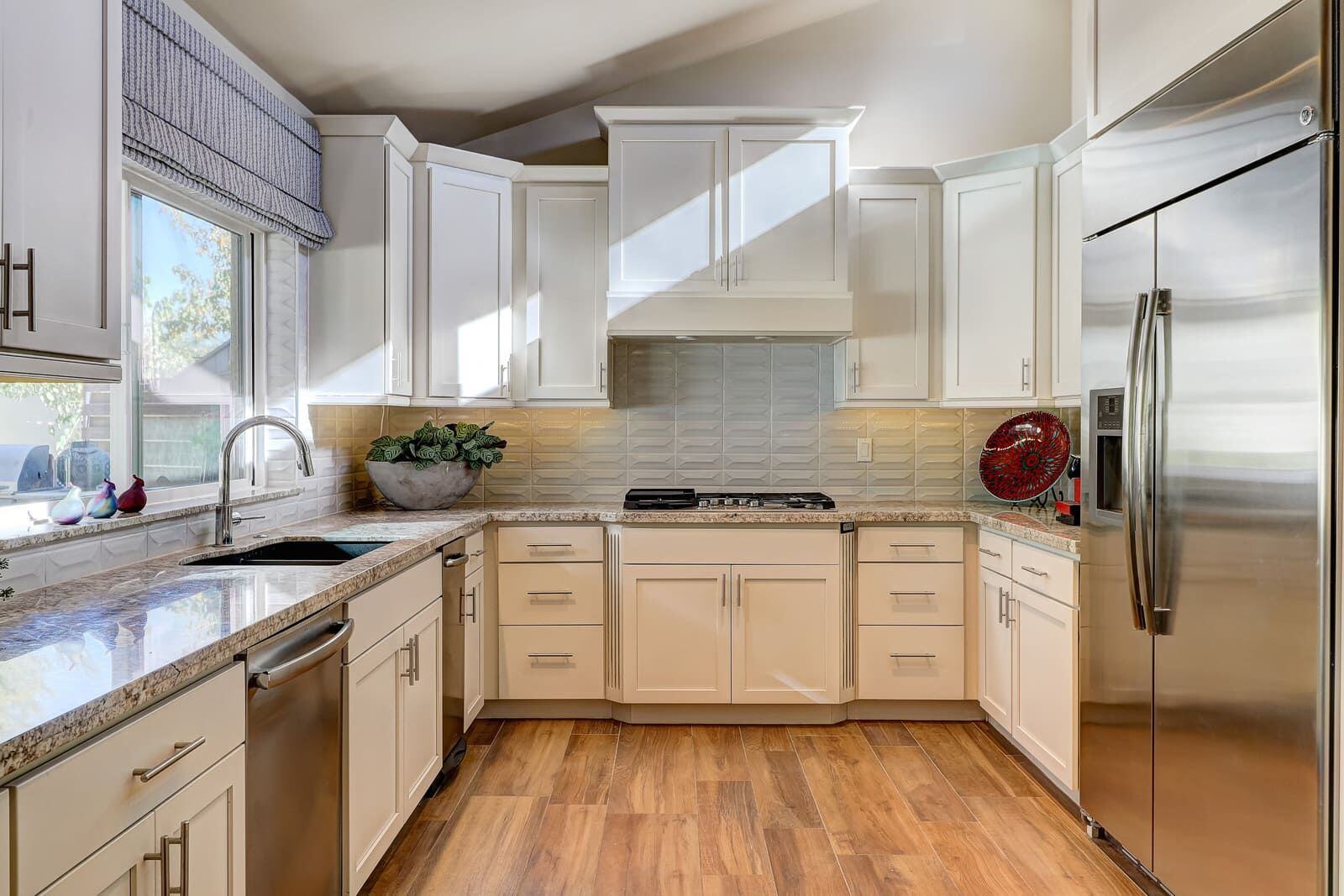 White kitchen cabinets with large stainless steel refrigerator and oven at Dahlia Home Renovation by MGD Builders, Phoenix, AZ