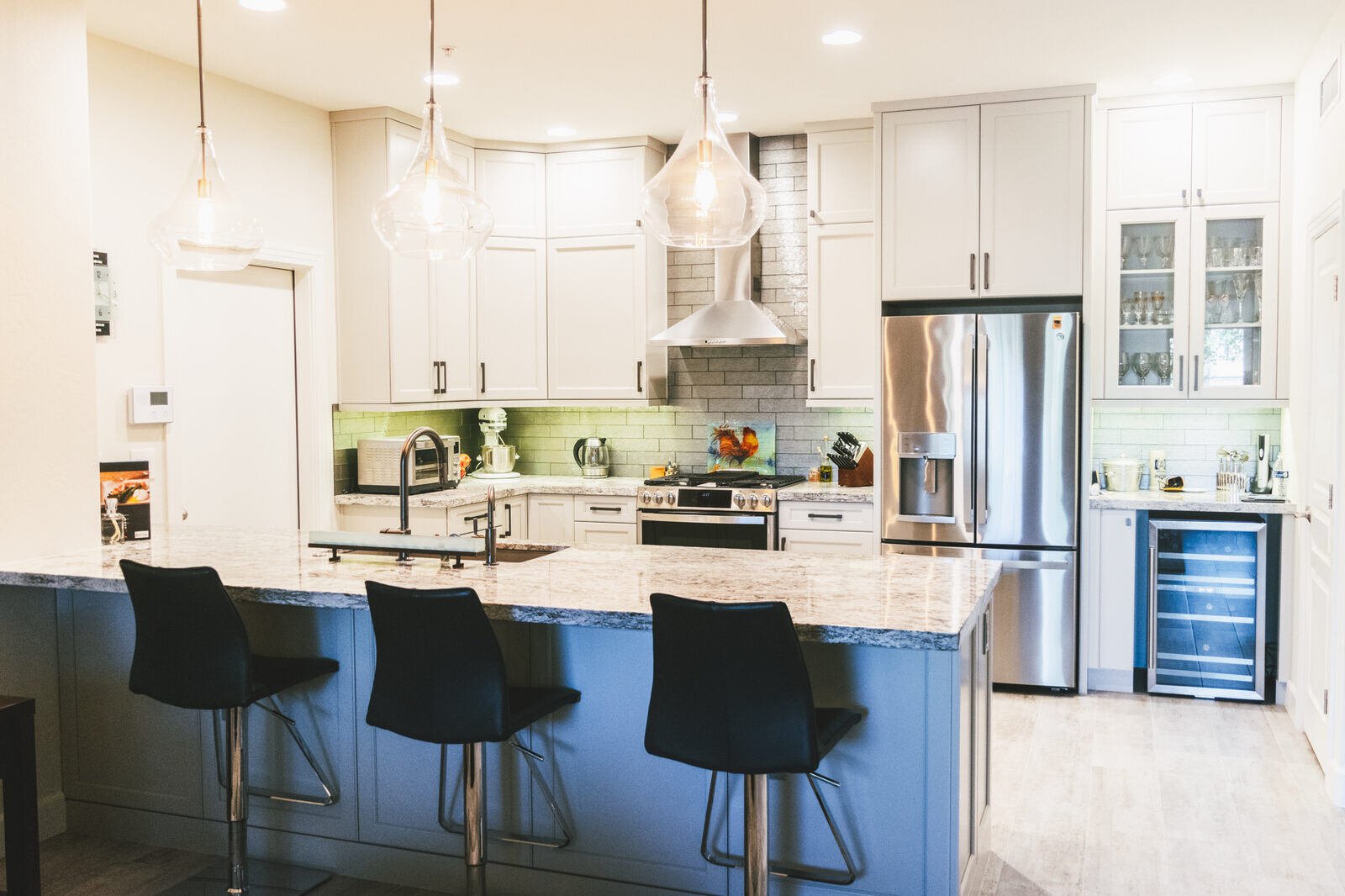 Full kitchen view with island, stainless steel appliances, and pendant lighting, remodeled by MGD Builders in Phoenix, AZ